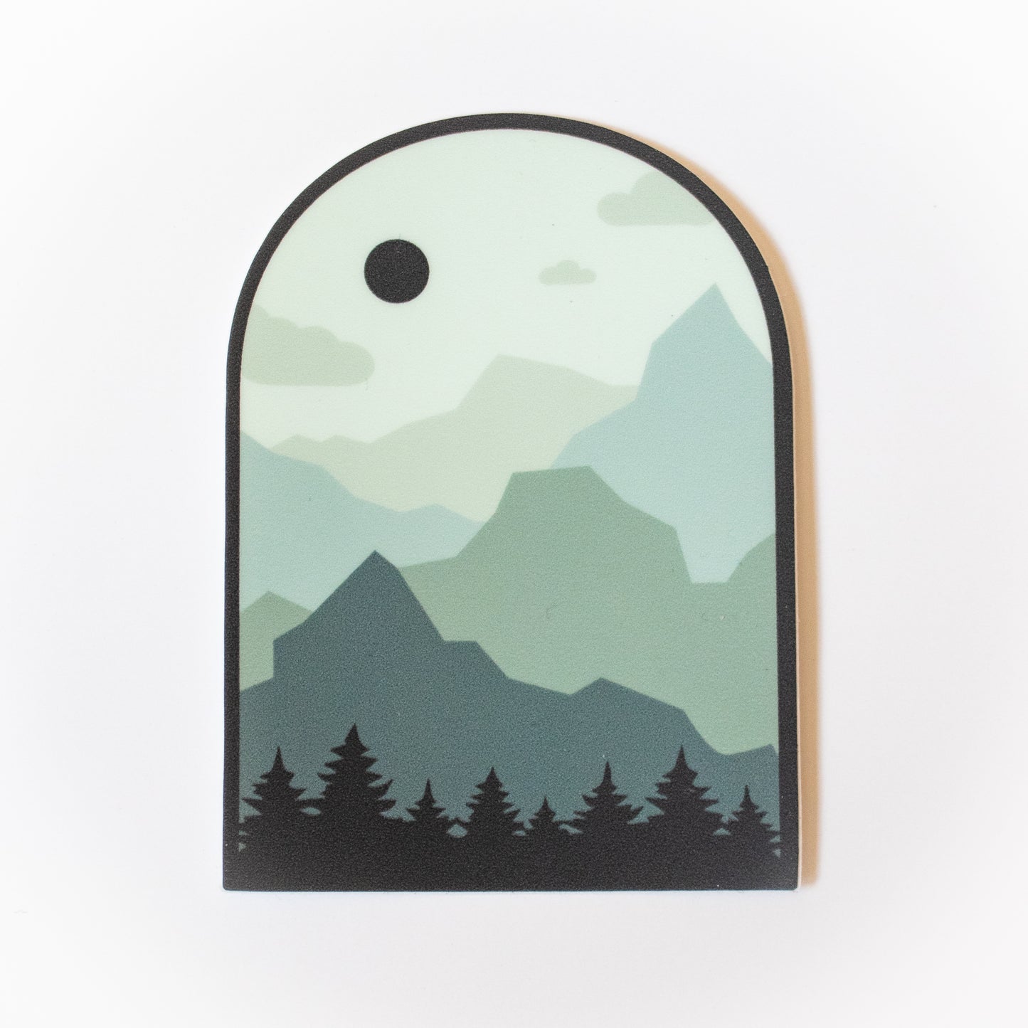 Monochromatic (varying shades of a single color) design in boho style. Layers as follows: Pine trees, 4 layers of mountains, sky with a few clouds and a dark sun or moon